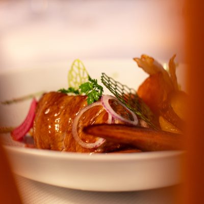 Image montrant le plat "Petit quasi de veau" du restaurant Les Oies Sauvages. Une pièce de veau tendre, accompagnée de son flan de lentilles corail, de ses légumes rôtis et d'un jus de viande aux abricots secs parfumé au thym.