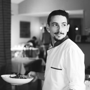 Théo Hennequin, chef du restaurant Les Oies Sauvages à Colomiers, posant fièrement avec une assiette, le regard au loin