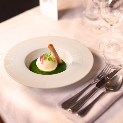 Image montrant l'entrée "L'œuf façon Florentine" du restaurant Les Oies Sauvages. Un œuf mollet, accompagné de son petit jus d’épinard, d'une crème Mornay revisitée et d'un donuts à la ventrèche.